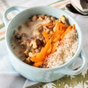 Oatmeal in a small bowl, garnished with walnuts, shredded carrots, and toasted coconut.