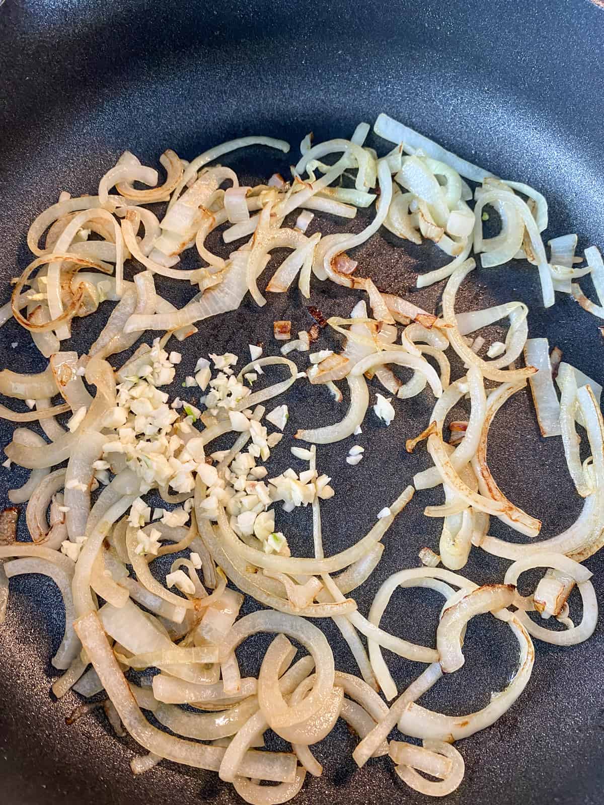 Minced garlic added to the skillet of sauteing onions.