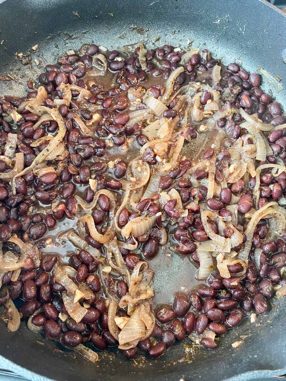 Black beans and onions, simmering in a skillet.