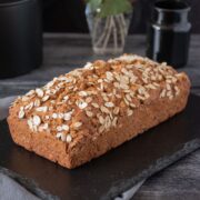 Whole, unsliced loaf of bread, sprinkled with oats.