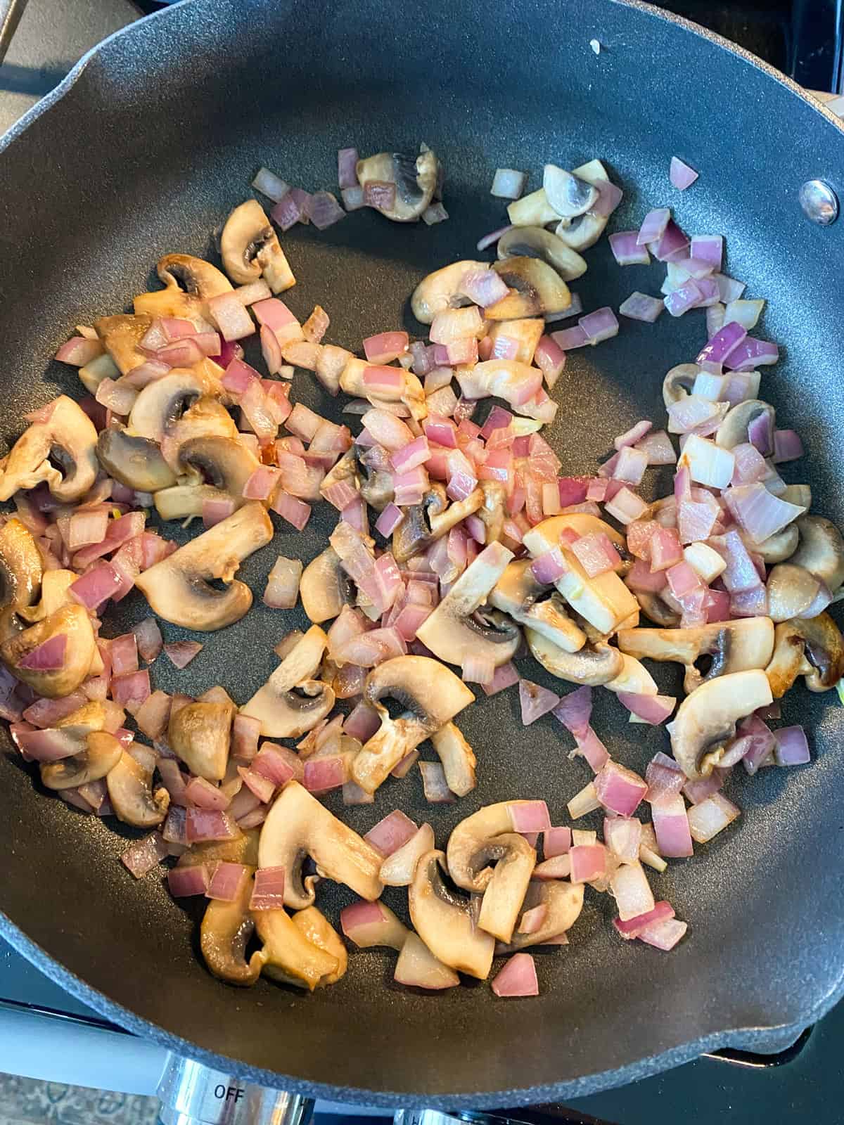 Mushrooms and onions sauteed in a skillet.