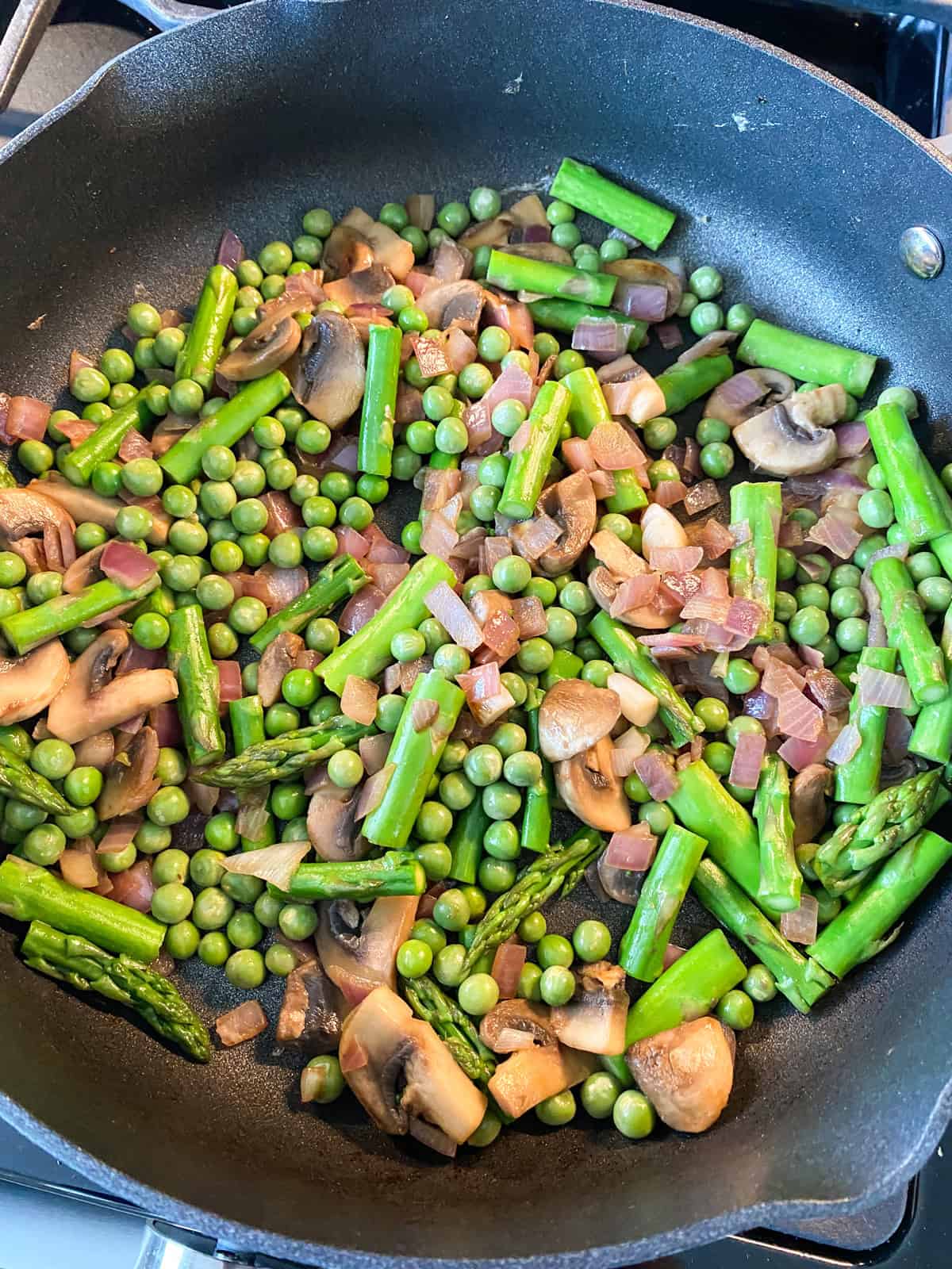 Asparagus and peas added to the skillet.