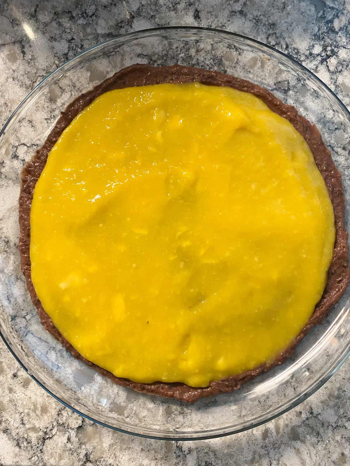 Dish with black bean dip and mango puree layered over.