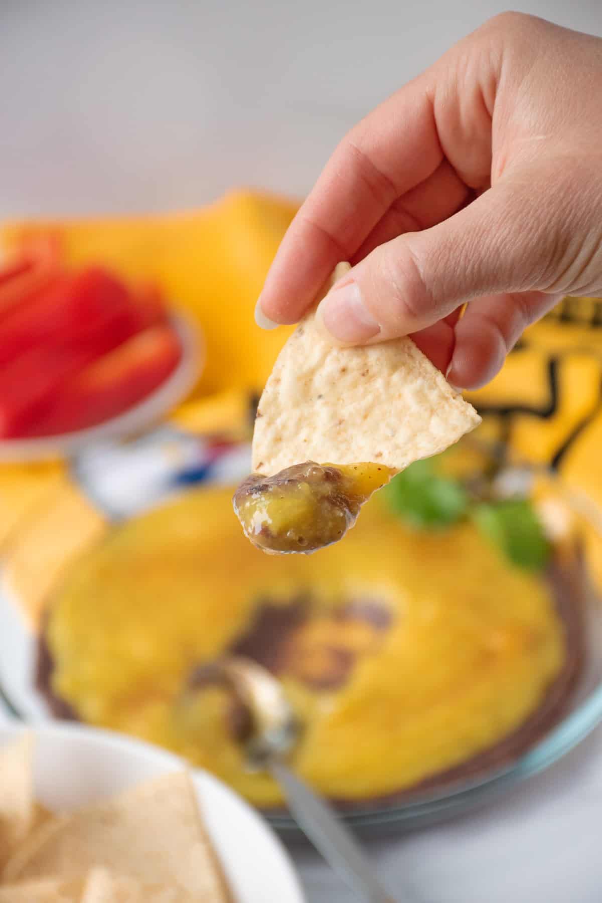 Black bean and mango dip on a tortilla chip, being held up close.