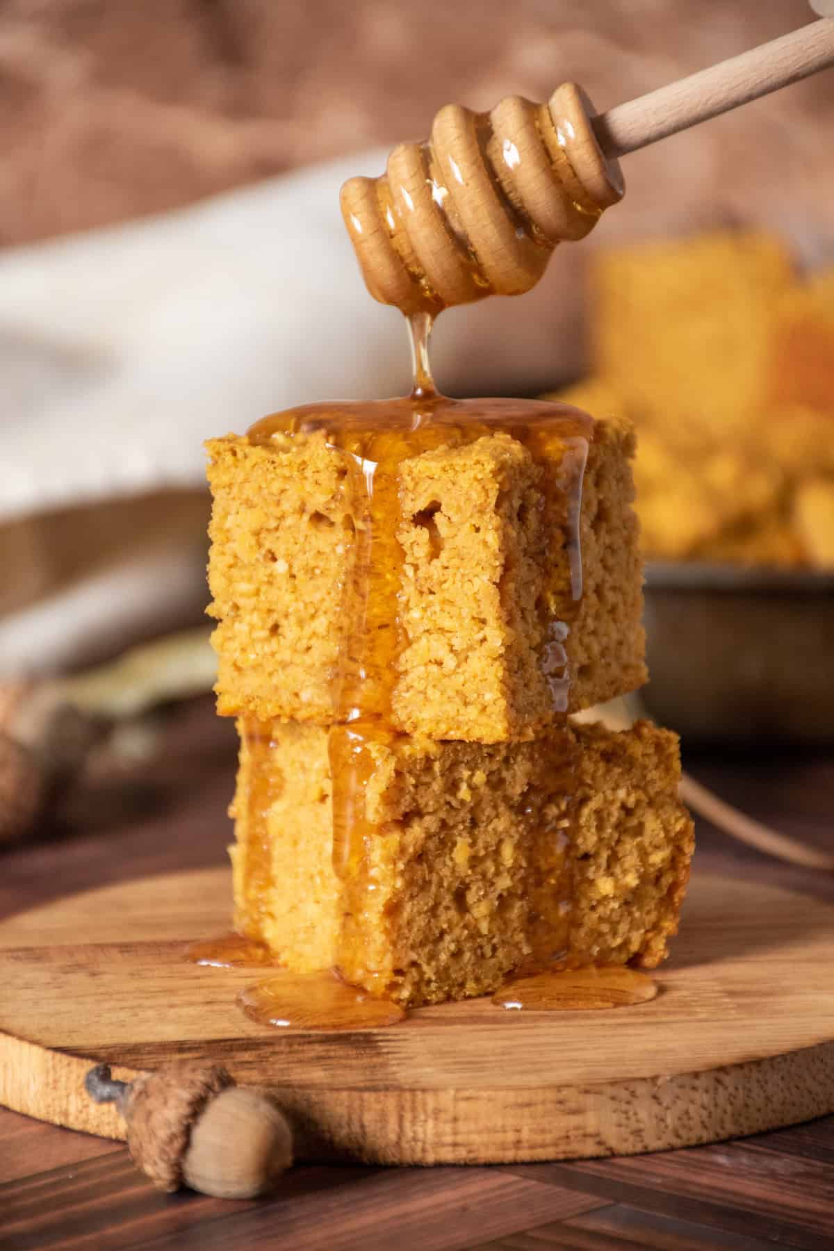 2 slices of cornbread stacked on one another, with honey being drizzled over them.