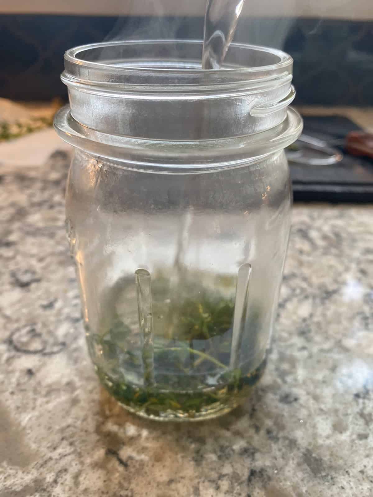 Pouring water into a jar, over the chopped thyme.