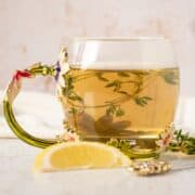 Tea in a glass mug, with thyme sprigs in it.