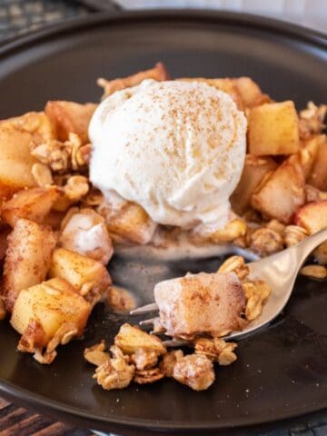 Pear apple crisp on a dish, with a scoop of vanilla ice cream.