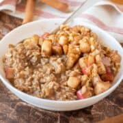 Bowl of oatmeal with sauteed apples and walnuts on top.
