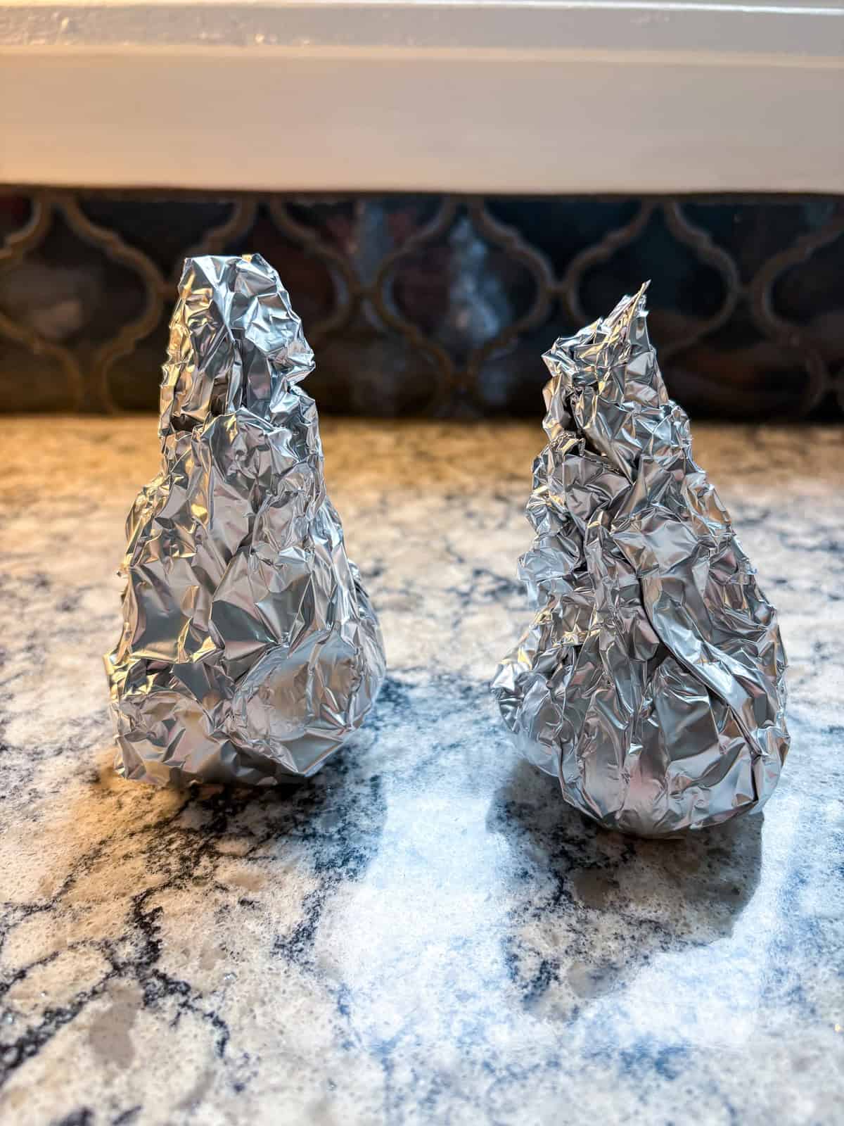 Garlic heads wrapped in foil for roasting.