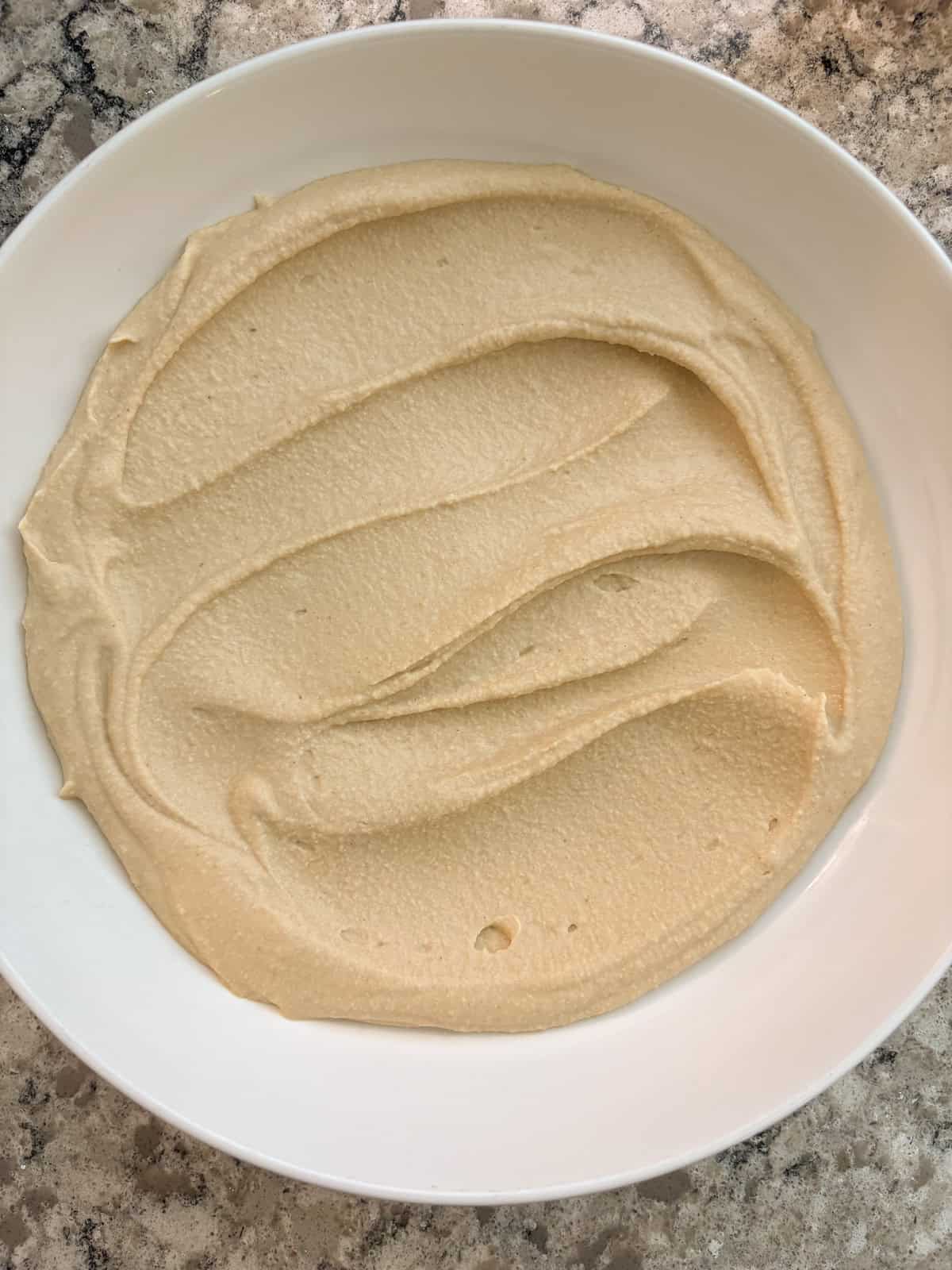 Hummus spread into a bowl.