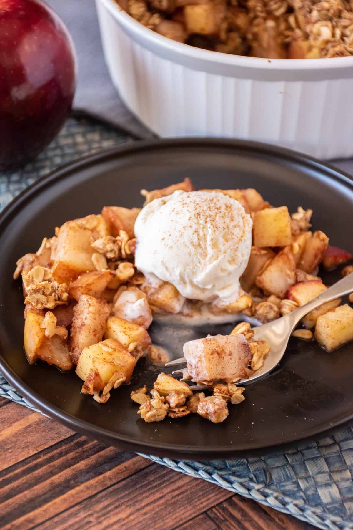 Pear apple crisp on a dish, with a scoop of vanilla ice cream.