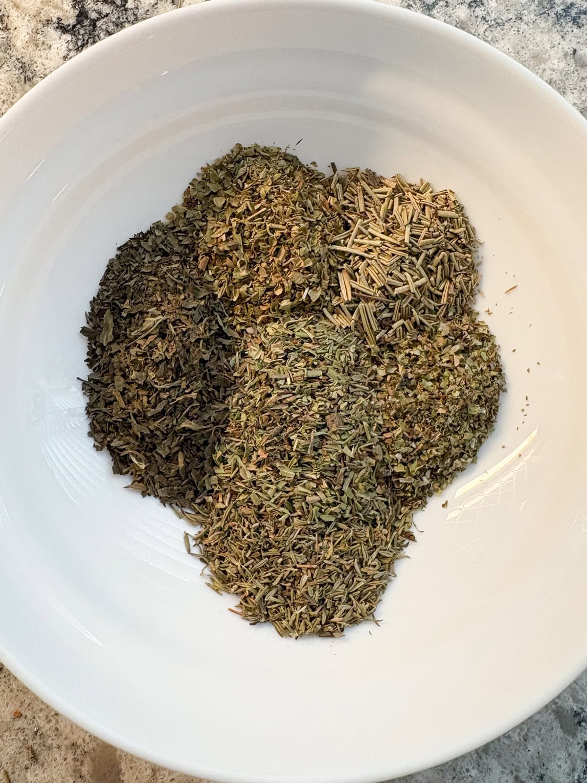 Individual herbs added to a bowl, before mixing.