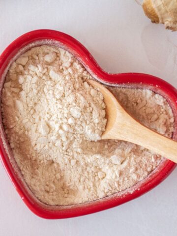 Seasoning powder made from pears and ginger, in a red heart shaped dish with a small wooden spoon.