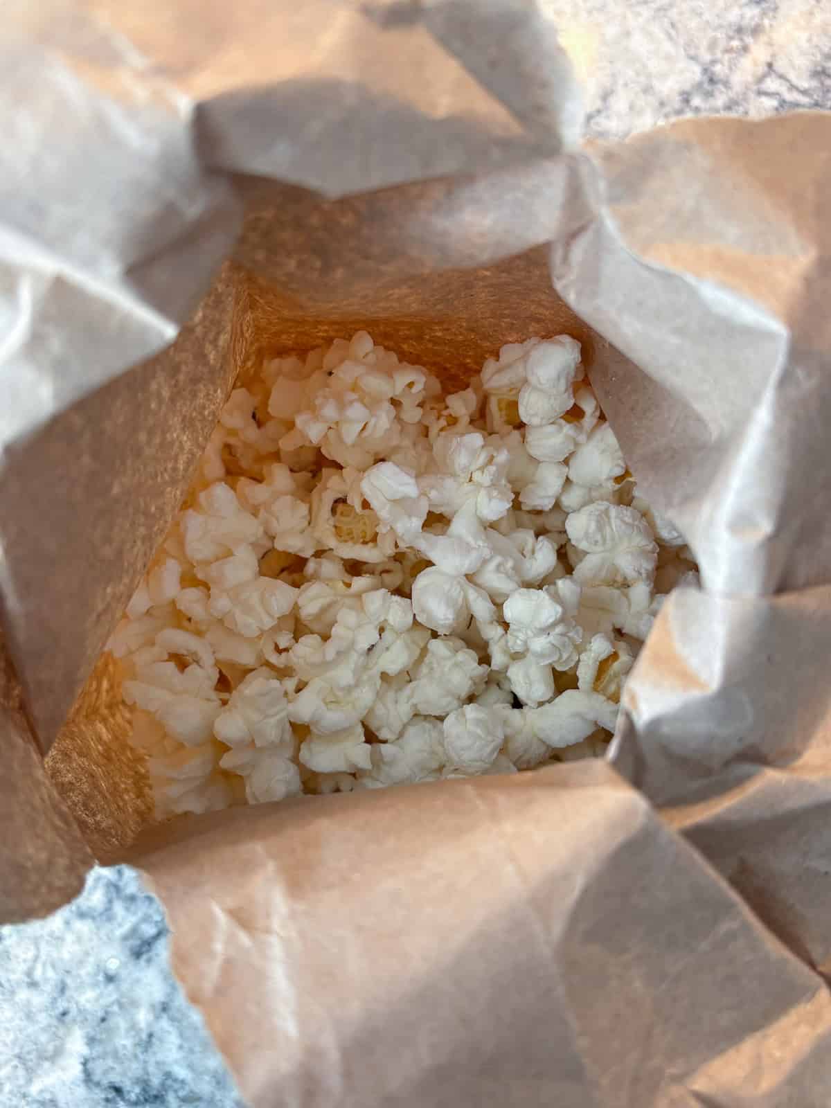 Popped popcorn in a brown paper lunch bag.