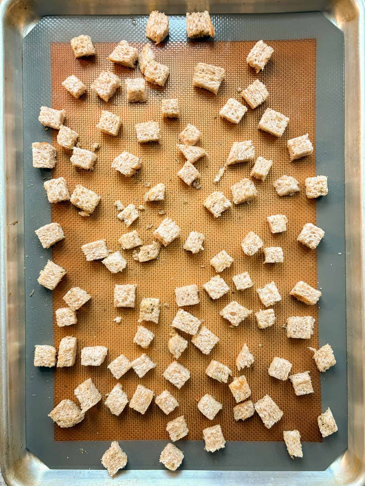 Bread cubes tossed with oil and seasoning, and spread on a baking sheet.