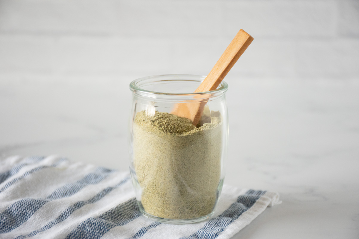 Small glass jar of ranch seasoning with a small wooden spoon in it.