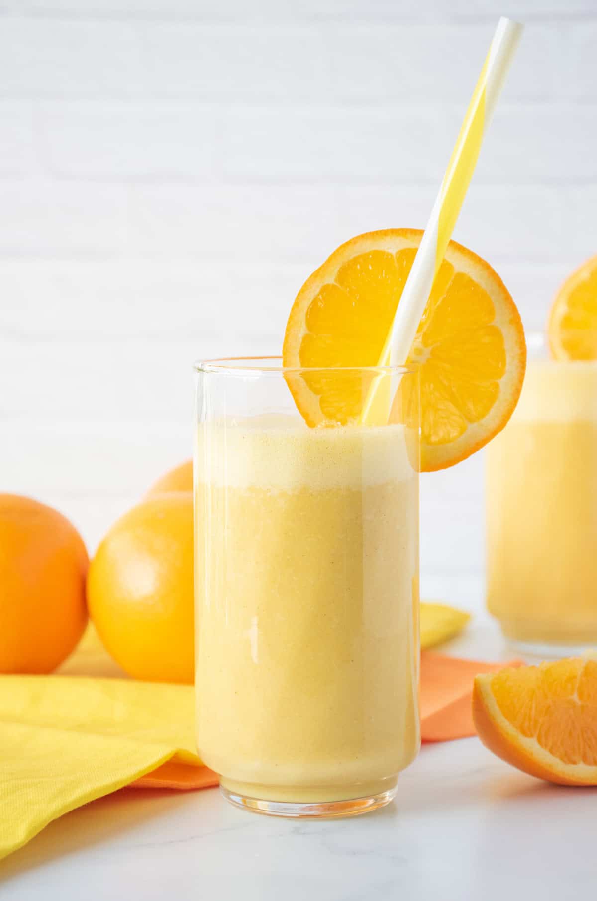 Orange drink in a glass with a straw, garnished with an orange slice.