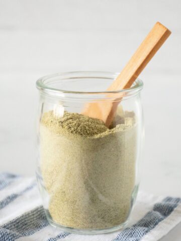 Small glass jar of ranch seasoning with a small wooden spoon in it.