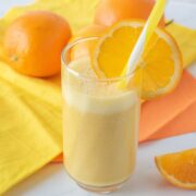 Orange drink in a glass with a straw, garnished with an orange slice.