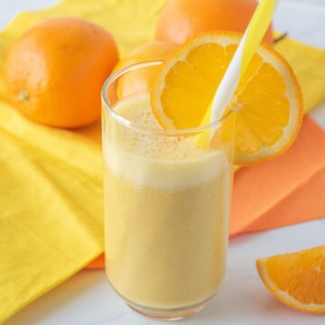 Orange drink in a glass with a straw, garnished with an orange slice.
