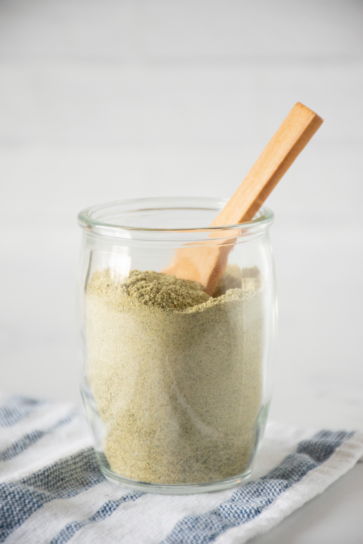 Small glass jar of ranch seasoning with a small wooden spoon in it.